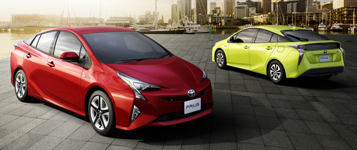 Two Toyota Prius cars parked by a waterfront city