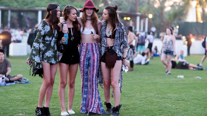 Four young women in festival attire on a grassy field