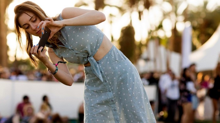 Woman in polka dot dress taking a photo with her phone