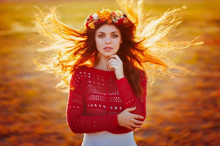Woman with flower crown and red sweater in autumn wind