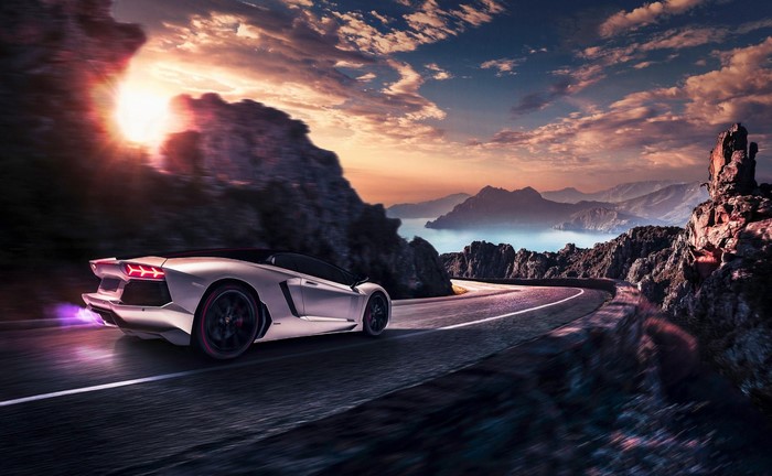 White Lamborghini Aventador driving on a coastal road at sunset
