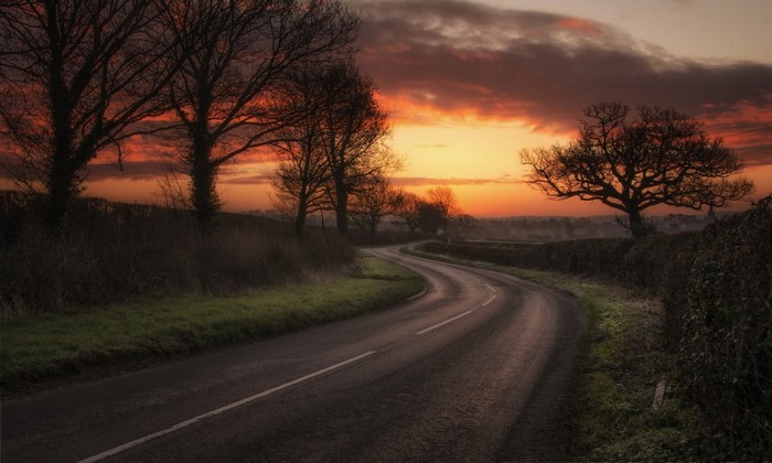 Winding road through rural landscape at sunset