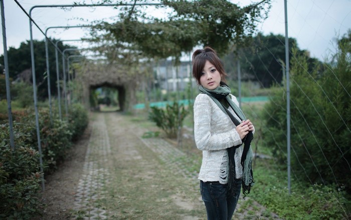 Asian woman in sweater and scarf in garden tunnel