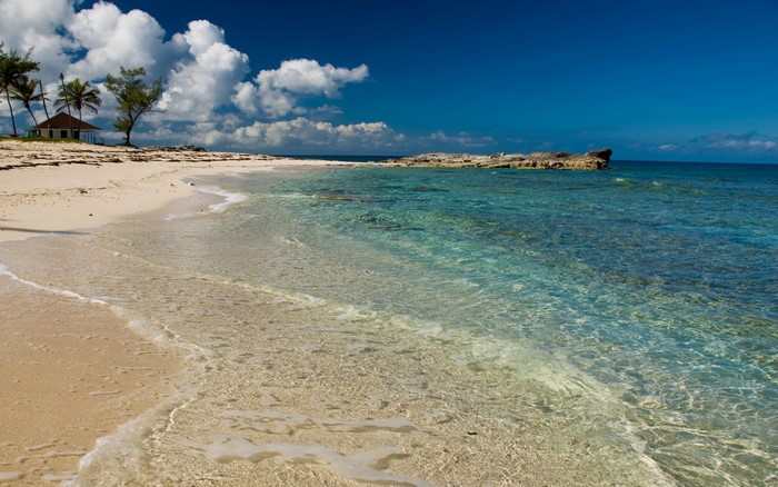 Beach with clear turquoise water and a small house