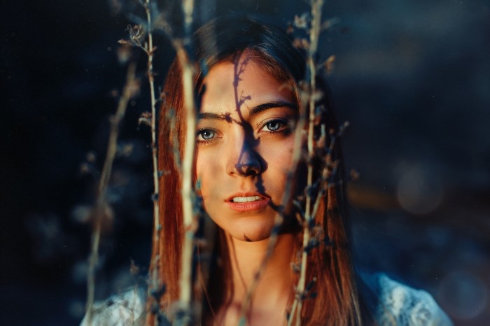 Woman with blue eyes behind branches