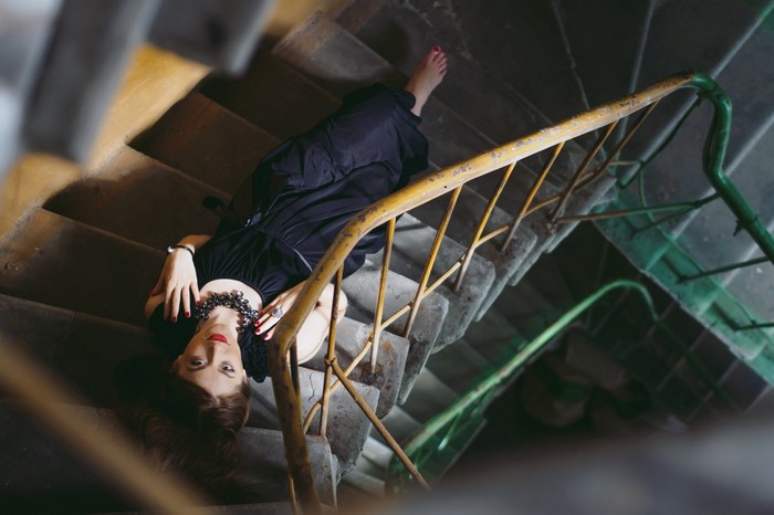 Woman in black dress lying on concrete stairs