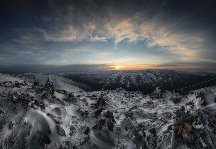Snowy mountain range at sunset with dramatic clouds