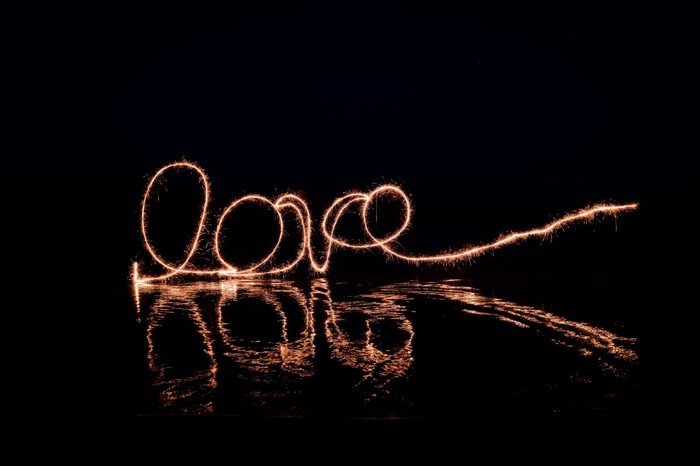 Sparkler light painting of the word "love" over water