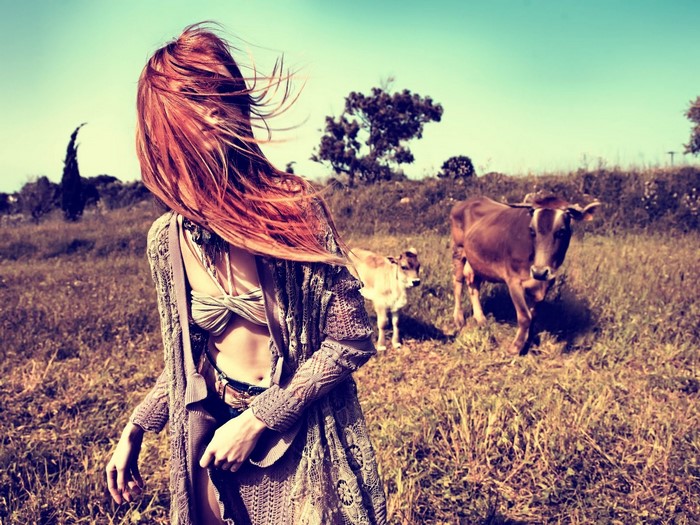 Woman with red hair and cows in a field