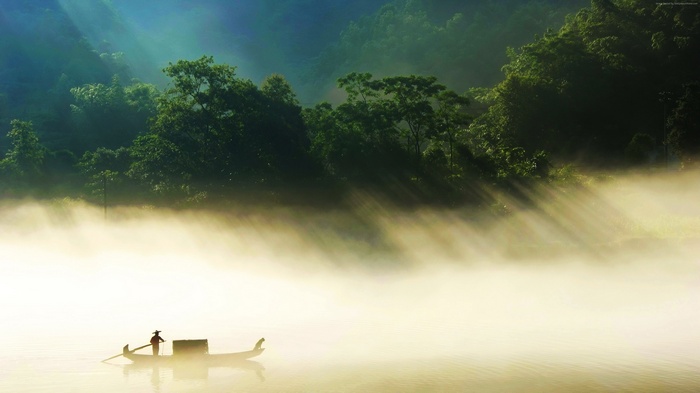 Boat on a foggy river with sunbeams