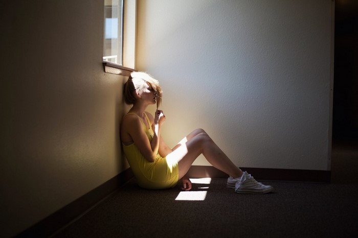 Woman in yellow dress sitting by window with light