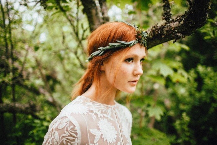Woman with red hair and flower crown in forest