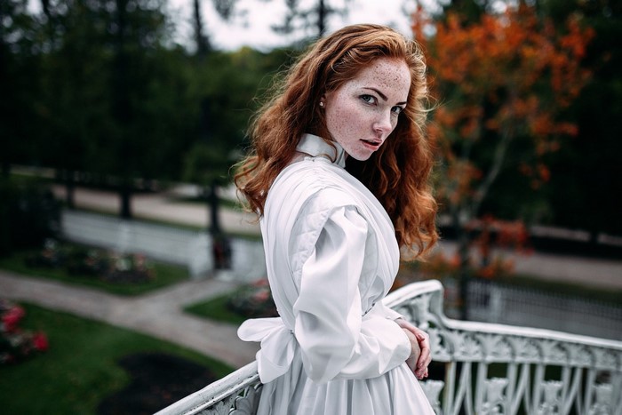 Woman with red hair and freckles in a white dress