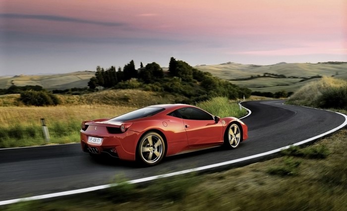 Red Ferrari 458 Italia driving on a winding road