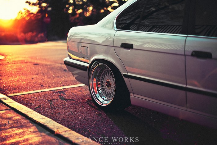 White BMW Sedan with Custom Wheels at Sunset