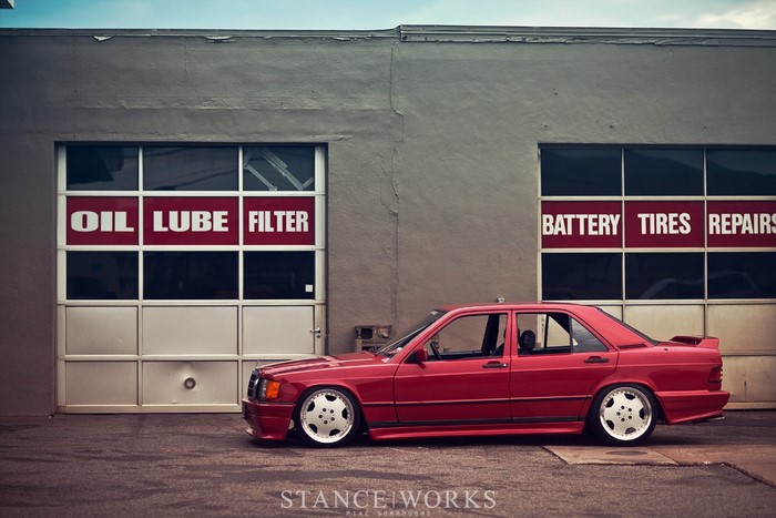 Red Mercedes-Benz 190E in front of auto repair shop