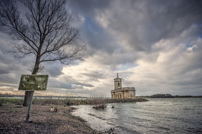 Building on a rocky outcrop in a lake under a cloudy sky