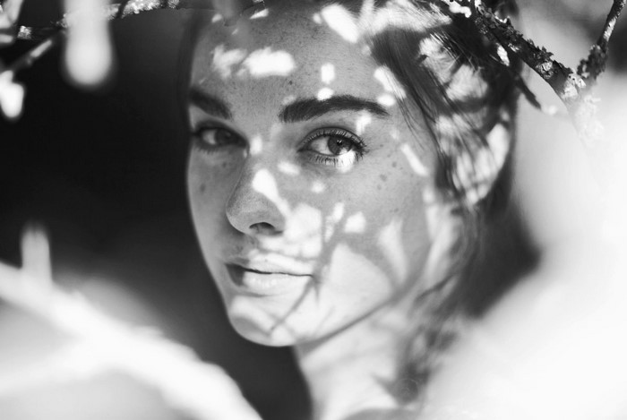 Monochrome portrait of a woman with freckles and dappled sunlight