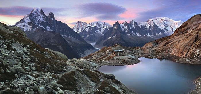 Mountain range with lake and hut at sunset