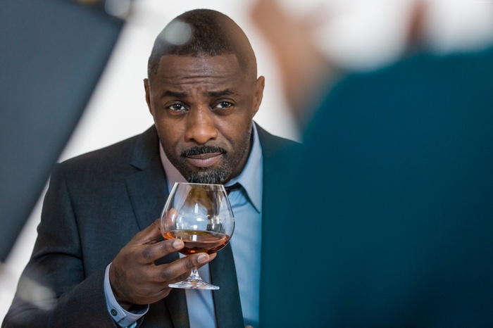Idris Elba holding a glass of whiskey