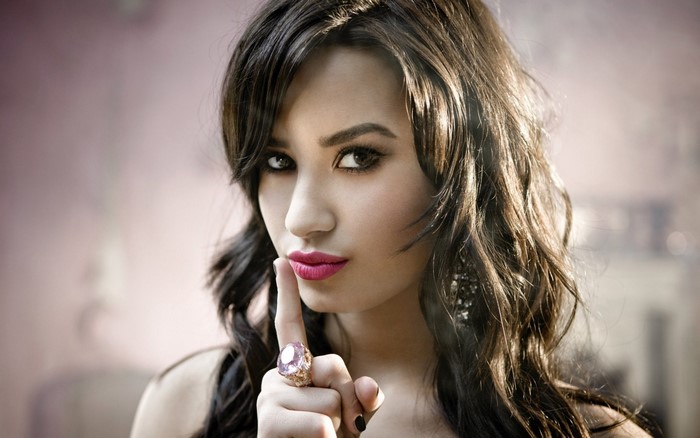 Demi Lovato with finger to lips and large ring