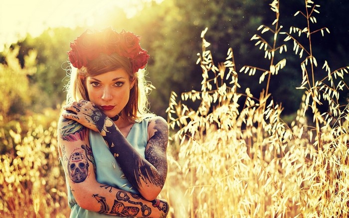 Woman with flower crown and tattoos in a field