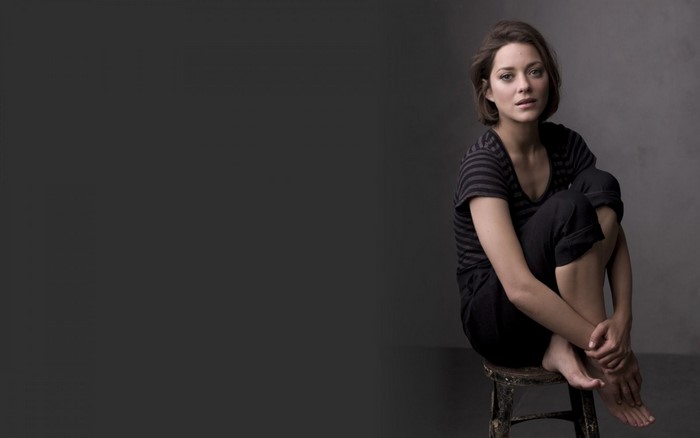 Marion Cotillard sitting on a stool