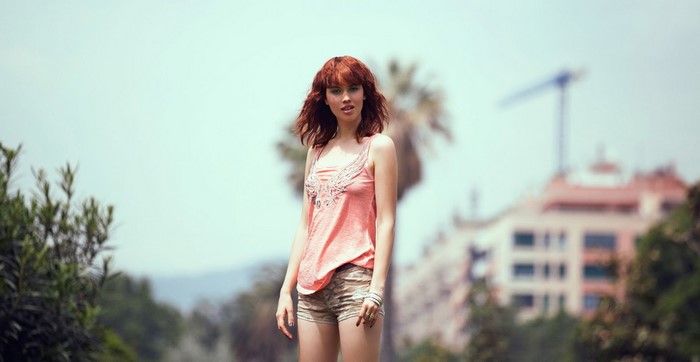 Woman with red hair wearing a pink tank top and shorts