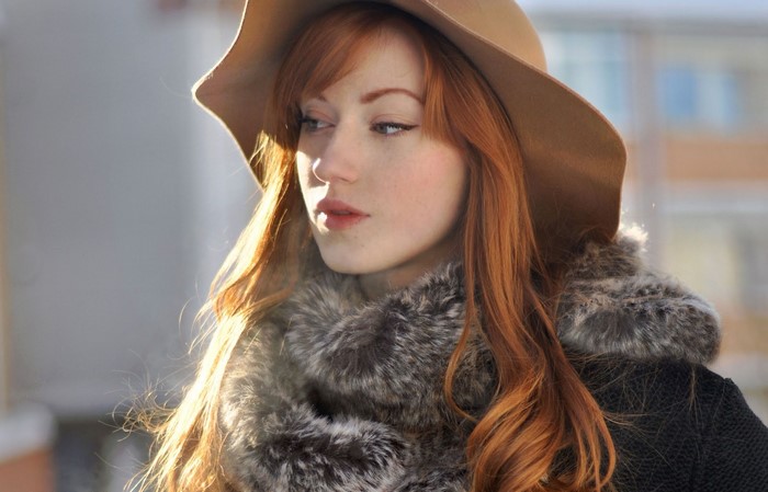 Woman with red hair wearing a hat and fur collar
