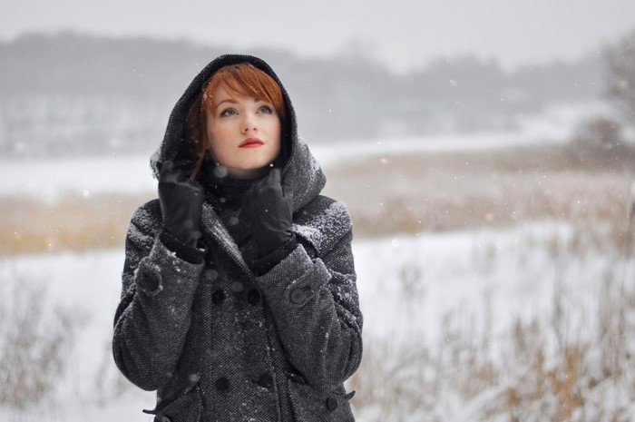 Woman with red hair in a hooded coat in the snow