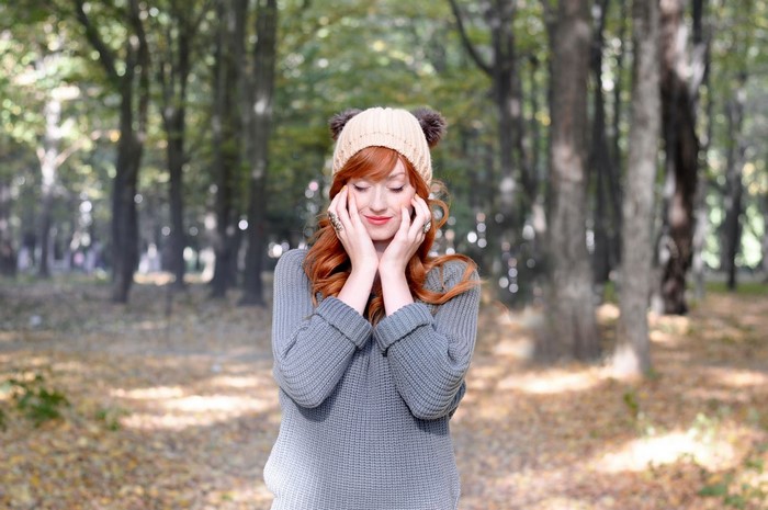 Woman with red hair wearing a hat in a forest