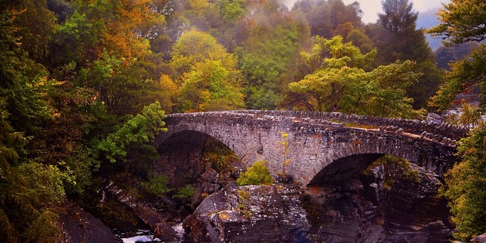 Stone bridge over a river in an autumn forest