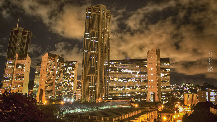 Cityscape at night with illuminated skyscrapers and clouds