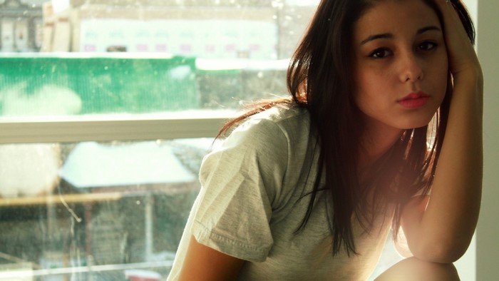 Woman with long brown hair by the window
