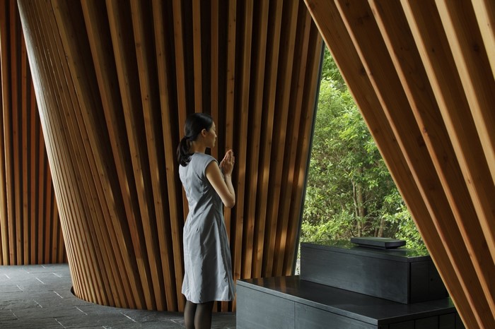 Woman praying in a wooden interior with a forest view