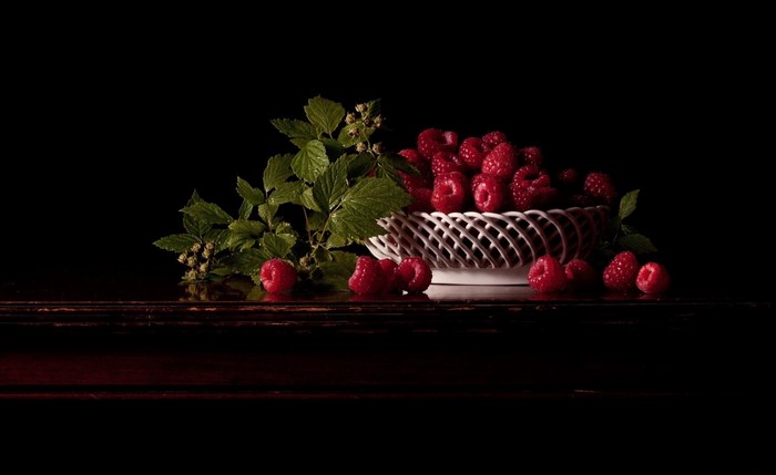 Still life of raspberries in a basket with leaves