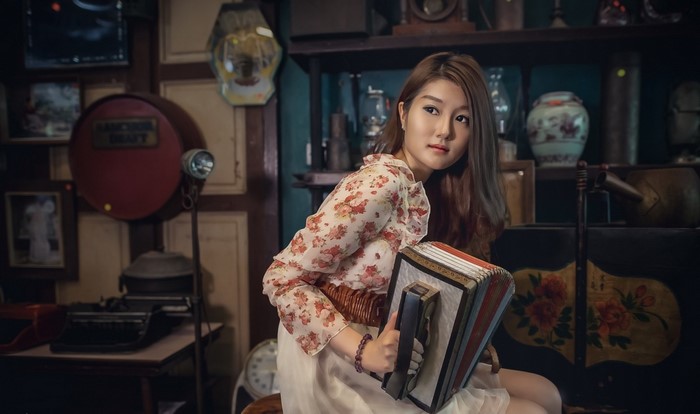 Asian woman holding an accordion in a vintage room