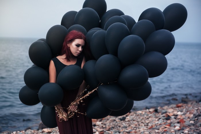 Woman with black balloons on a rocky beach