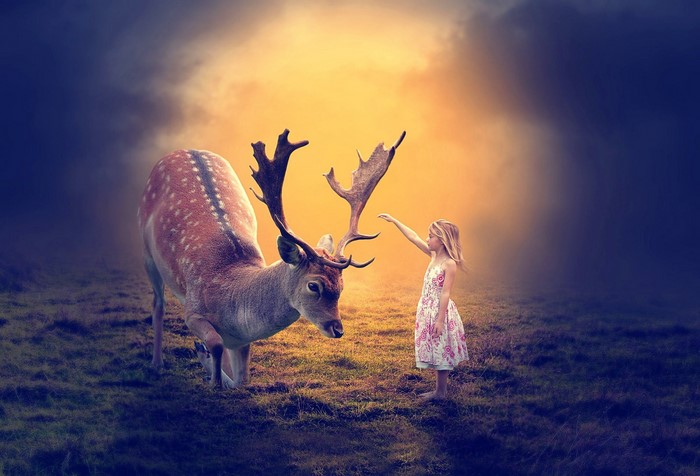 Girl reaching out to a deer in a fantasy landscape