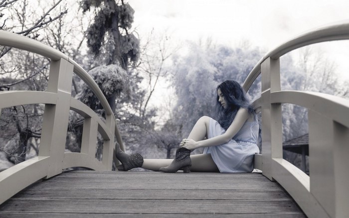 Woman sitting on a bridge in winter