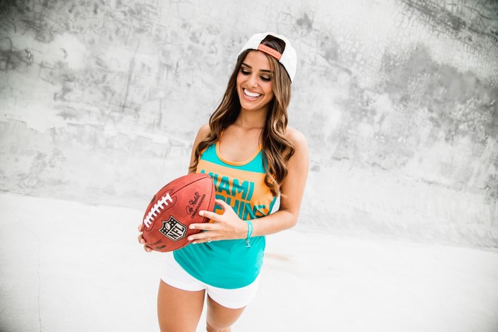 Woman in Miami Dolphins tank top holding football