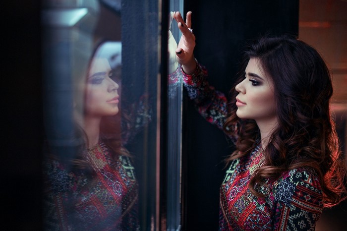 Woman looking at her reflection in glass