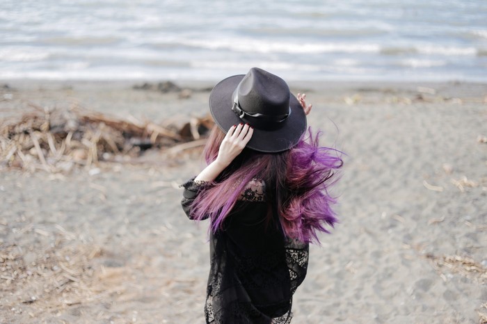 Woman with purple hair and hat on a beach