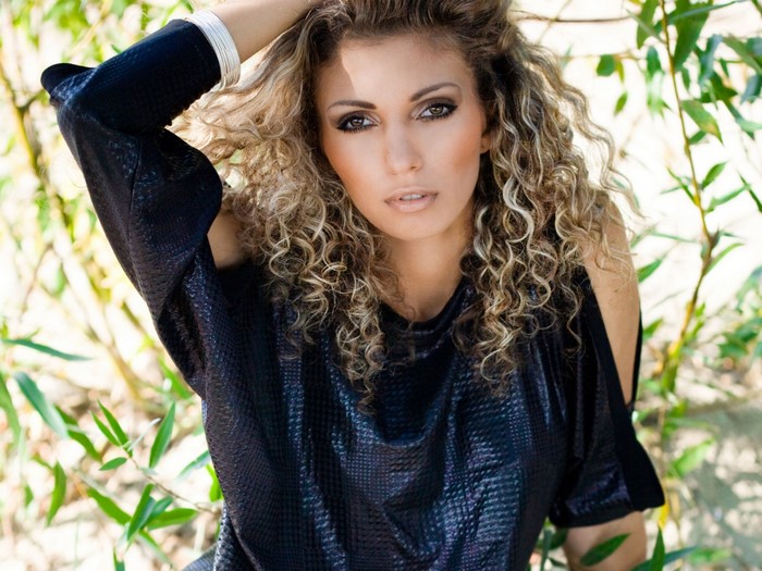 Woman with curly brown hair in a black dress