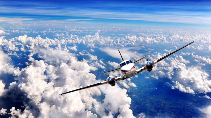 Twin-engine airplane flying above clouds