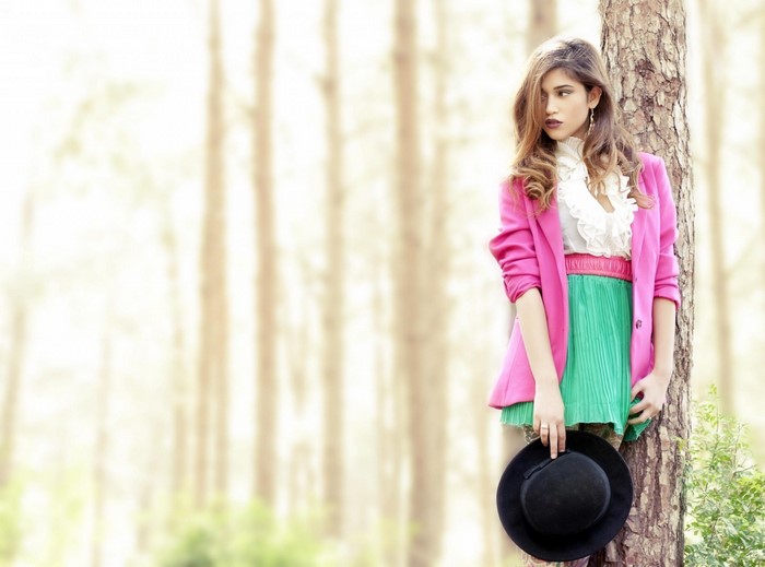 Woman in pink blazer and green skirt in forest
