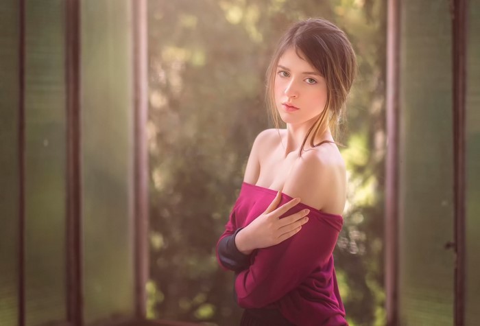 Young woman with off-the-shoulder top posing indoors