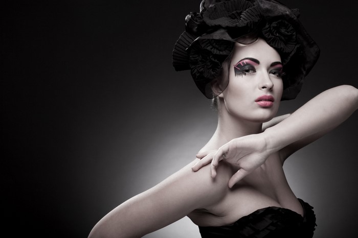 Woman with dramatic makeup and black headwear