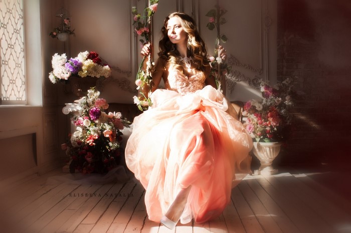 Woman in a pink dress on a swing with flowers