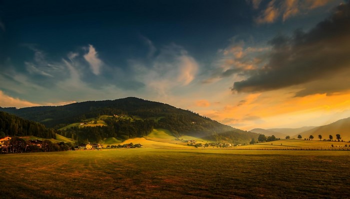 Sunset over a rural mountainous landscape with fields and forests